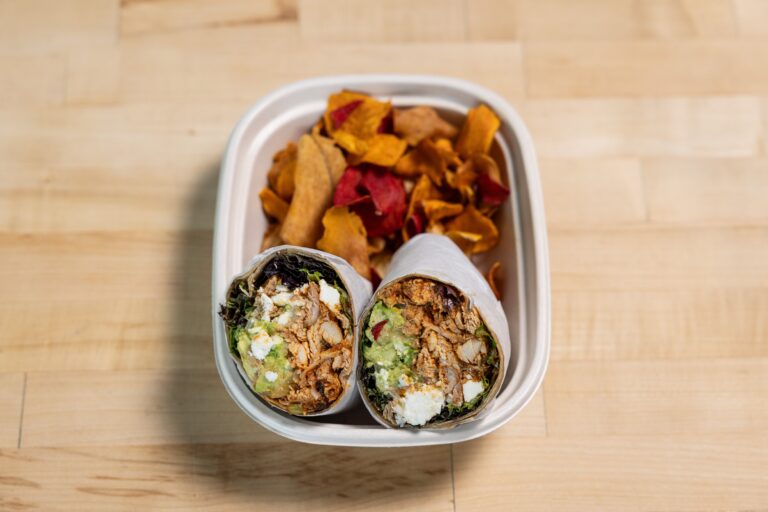 A wrap cut in half with sweet potato chips on the side.