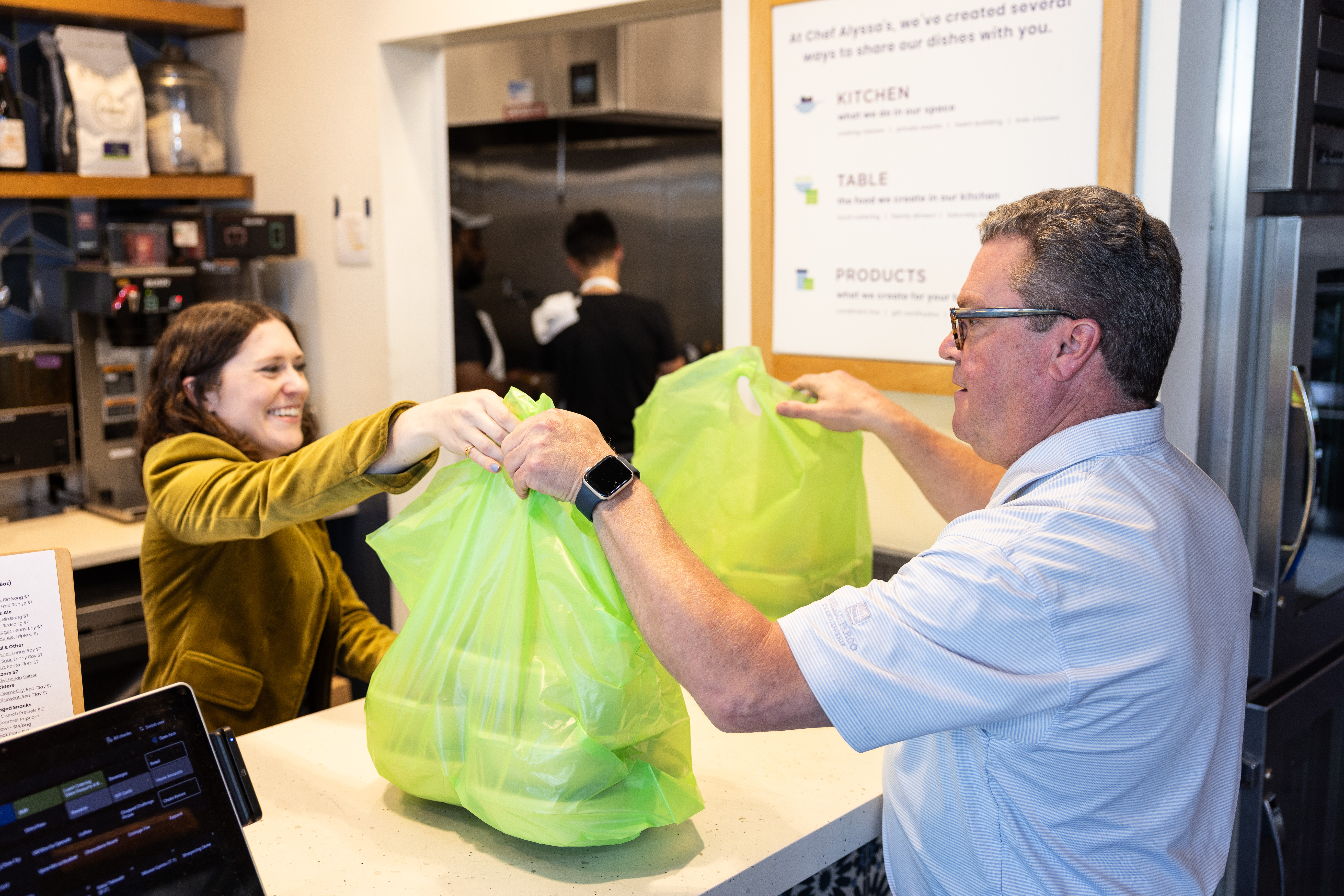 Catering coordinator handing bags of food to a customer.